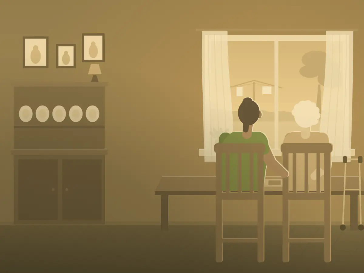 A support worker and her client sit together at a kitchen table by an open window.