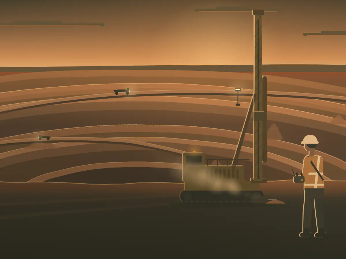 A driller in hi-vis works a blast-hole rig by remote on a bench of a red-earth open cut.