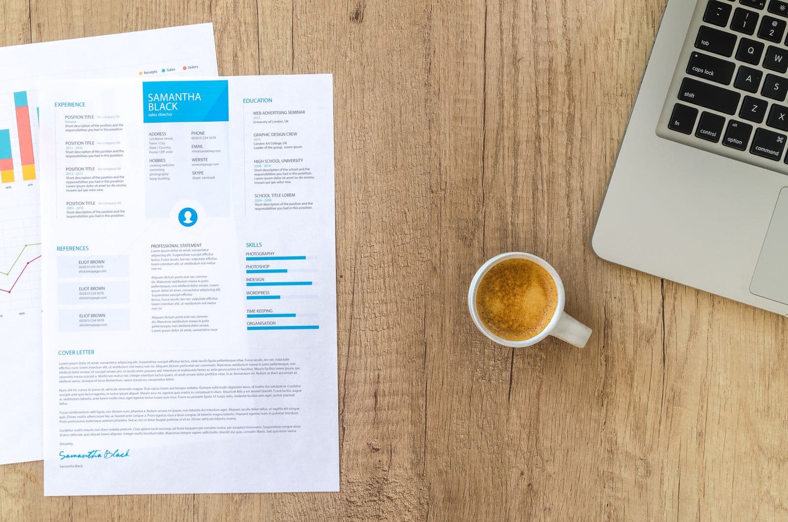 A printed resume beside a laptop and coffee on a timber desk