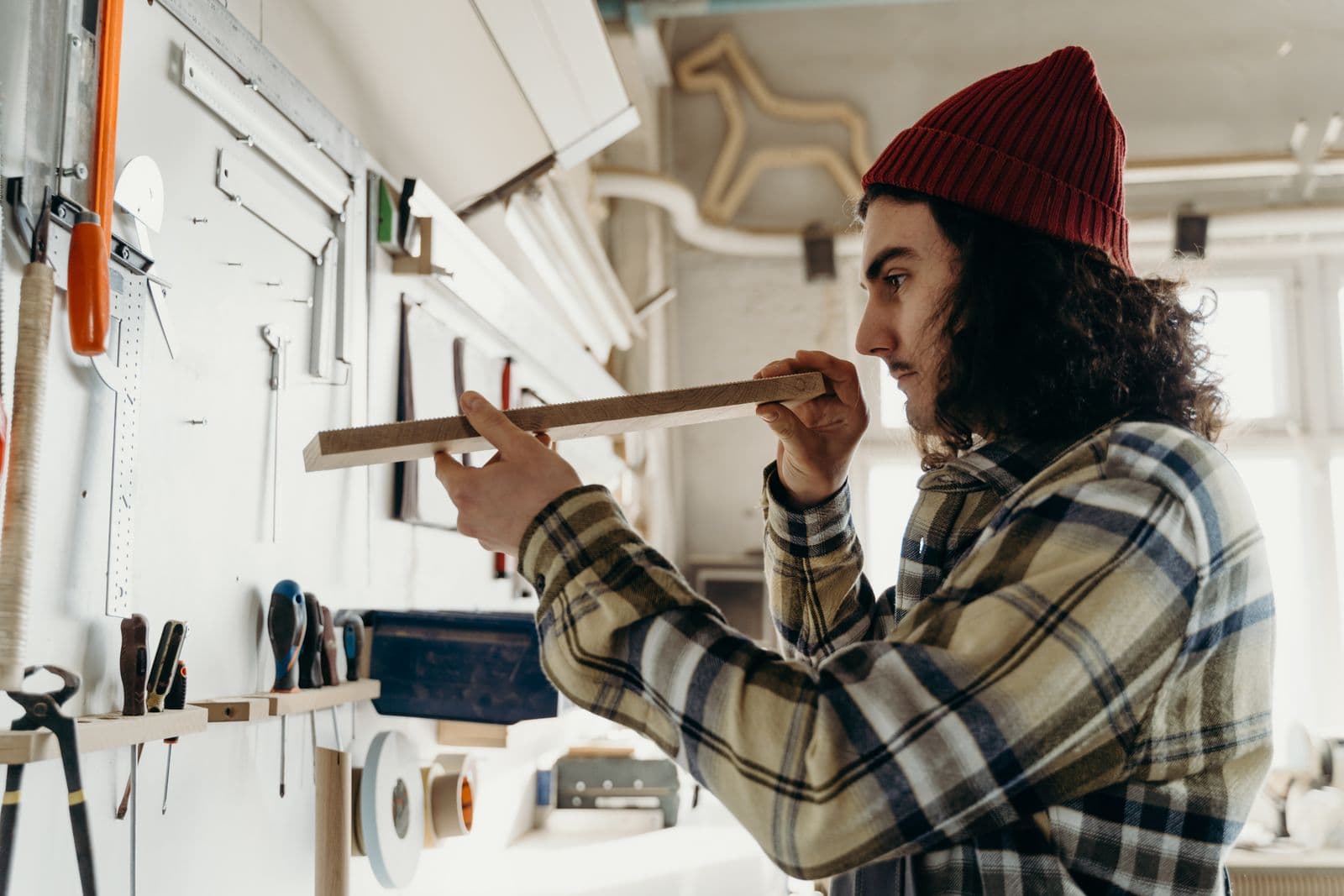 A carpenter measuring a timber plank in a workshop