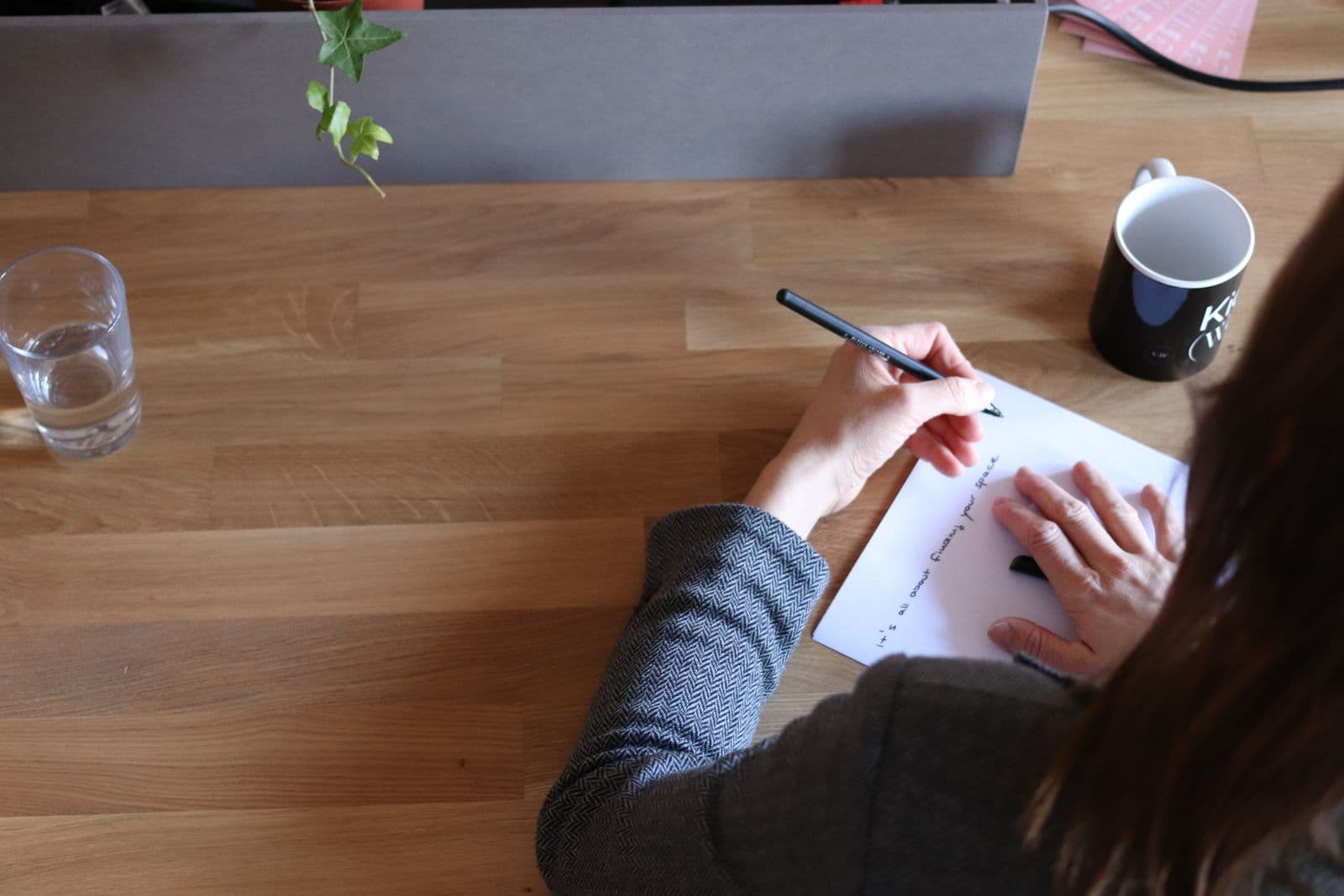 A woman writing notes at a timber desk