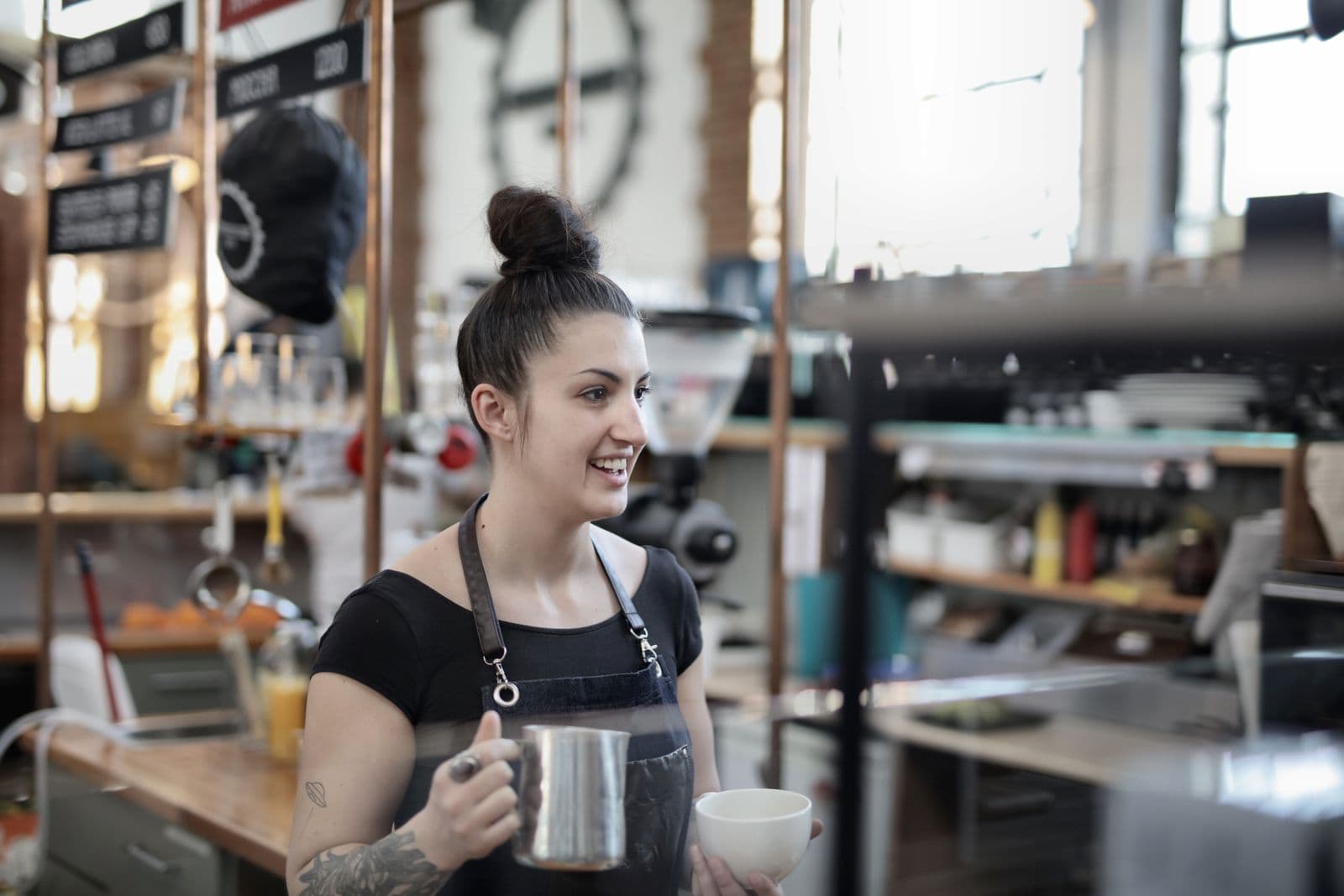 A barista smiling while making coffee at a cafe counter