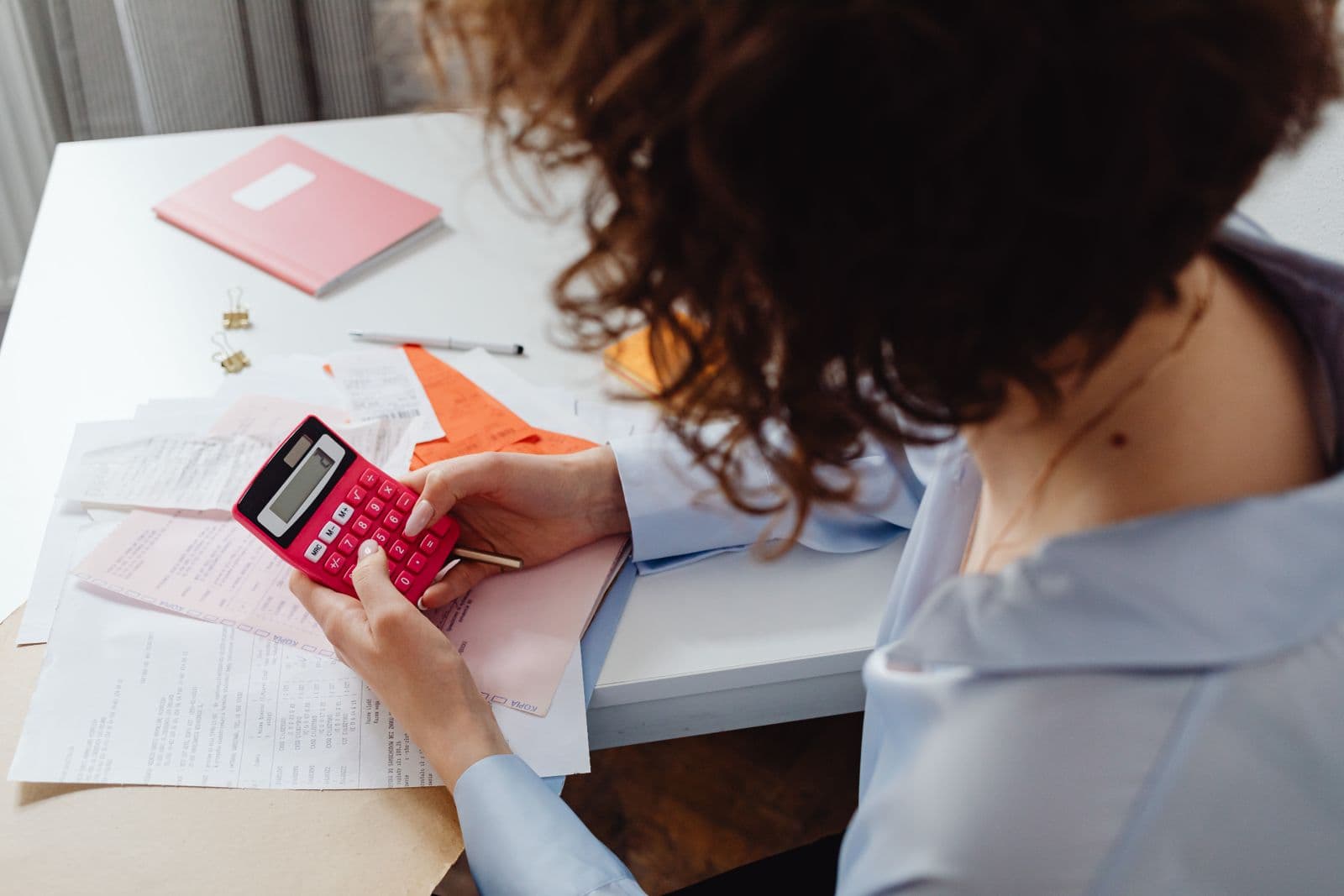 A woman working through figures with a calculator and documents