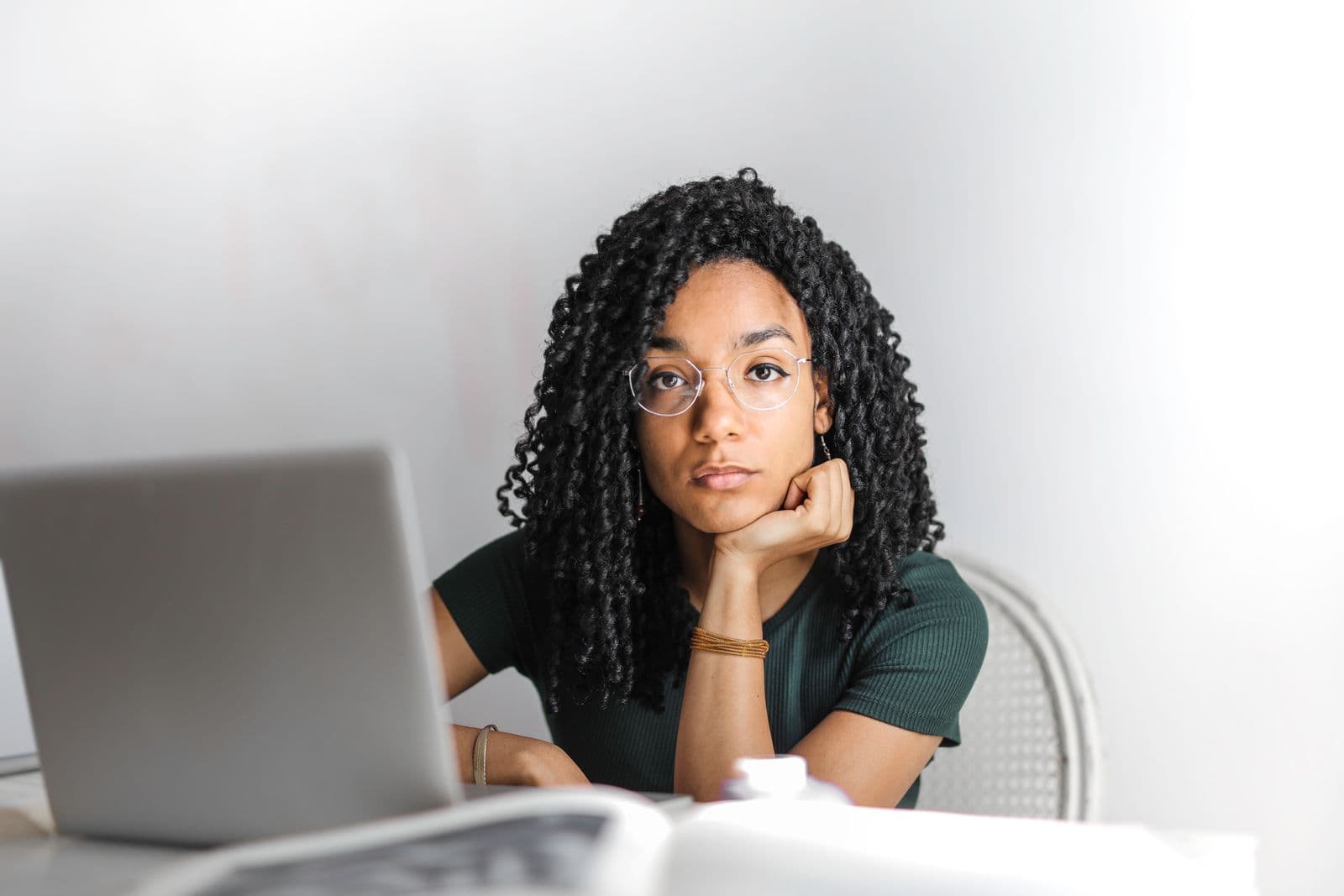 A woman waiting thoughtfully in front of her laptop